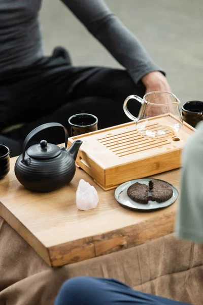 Vista cortada de chá pu-erh comprimido perto bule de chá e pessoas no estúdio de ioga — Fotografia de Stock