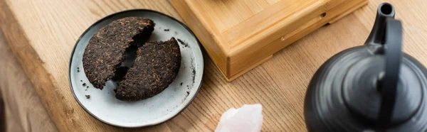 Vista superior del té comprimido pu-erh en el plato cerca de la tetera japonesa en el estudio de yoga, pancarta - foto de stock
