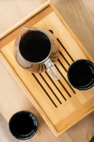 Vue du dessus du thé puer infusé dans une cruche en verre près des tasses japonaises — Photo de stock