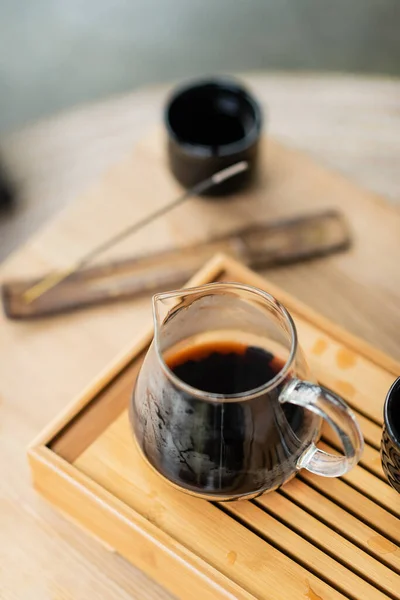 Vue grand angle du thé puer infusé concentré dans une cruche en verre sur un support en bois — Photo de stock