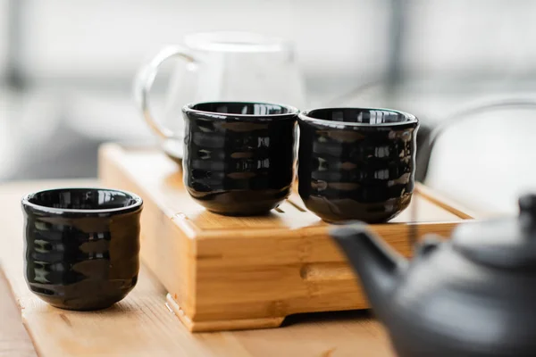 Традиционные японские чашки чая с puer рядом чайник на размытом переднем плане — стоковое фото