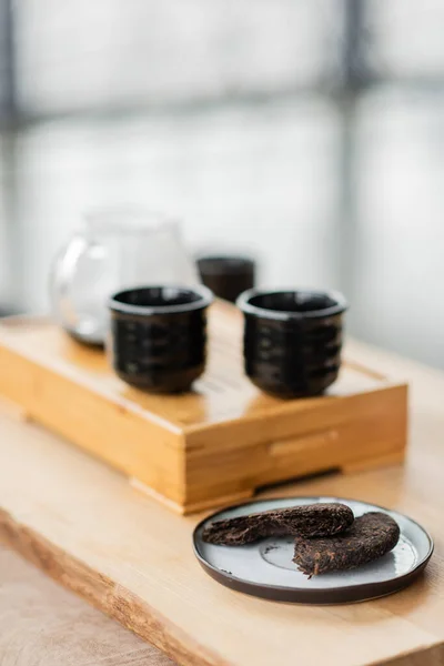 Сжатый чай пу-эх на тарелке возле японских чашек чая в студии йоги — стоковое фото