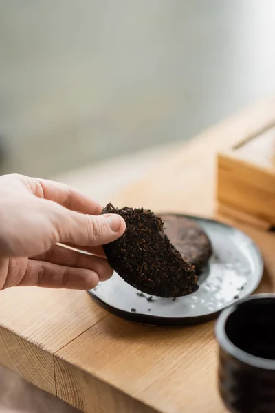 Cropped view of man taking piece on compressed puer tea — Stock Photo