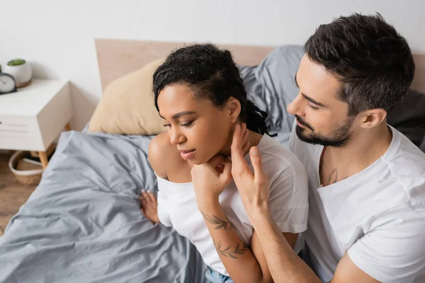 Vue grand angle de l'homme barbu touchant jeune femme afro-américaine dans la chambre à coucher à la maison — Photo de stock