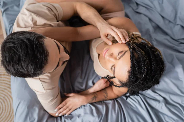 Top view of passionate african american woman in lingerie and man in t-shirt embracing in bedroom at home — Stock Photo