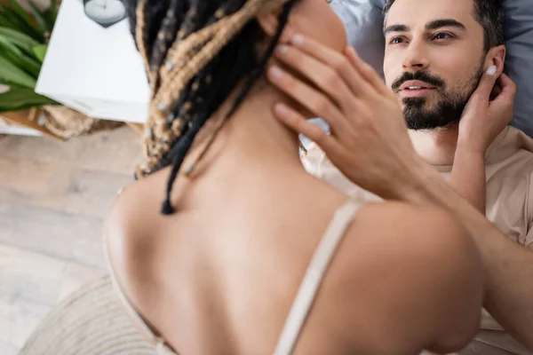 Alto ángulo vista de barbudo hombre mirando sexy africano americano mujer en borrosa primer plano en casa - foto de stock
