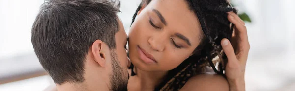 Charming african american woman with closed eyes near brunette man at home, banner — Stock Photo