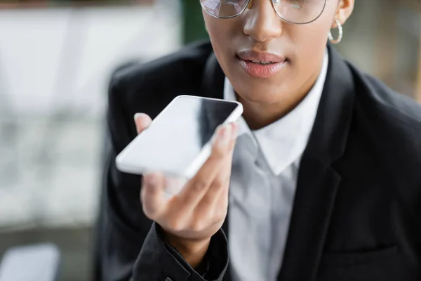 Обрізаний вид афроамериканської бізнес-леді, що надсилає голосове повідомлення на мобільний телефон в офісі — стокове фото