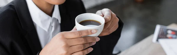 Visão parcial da empresária afro-americana segurando xícara de café preto no escritório, banner — Fotografia de Stock