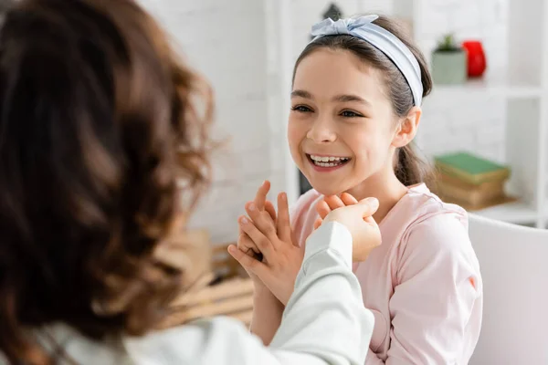 Terapeuta del habla borrosa trabajando con alumna alegre en la sala de consulta — Stock Photo