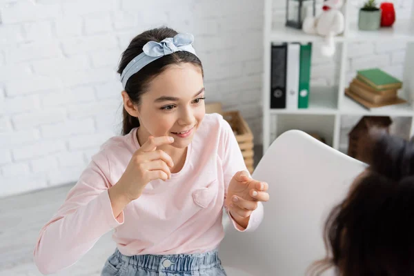 Carefree pupil taking to blurred speech therapist in consulting room — Stock Photo