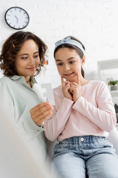 Preteen girl speaking near smiling speech therapist with letter in consulting room — Stock Photo