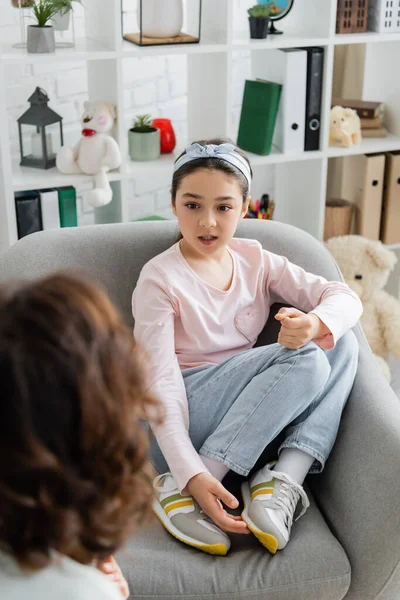 Preteen child talking to blurred psychologist in consulting room — Stock Photo