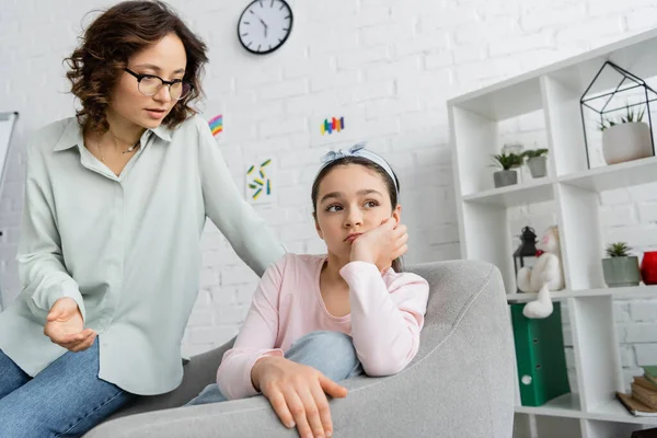 Psicólogo em óculos olhando para triste menina pré-adolescente em consultório — Fotografia de Stock
