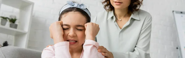 Enfant préadolescent en colère assis près de psychologue floue dans la salle de consultation, bannière — Photo de stock