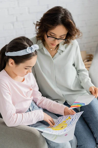 Preteen girl explaining drawings near psychologist in consulting room — Stock Photo