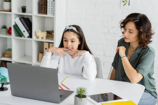 Женщина смотрит на дочь говорить во время урока логопедии онлайн дома — стоковое фото