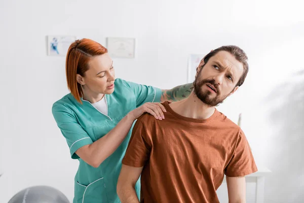 Reha-Spezialist untersucht schmerzhaften Hals des bärtigen Mannes bei Termin im Sprechzimmer — Stockfoto