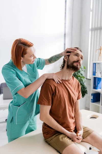 Physiotherapist stretching neck of patient during diagnostics in rehab center — Stock Photo