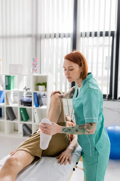 Osteopath massaging injured leg of man during rehabilitation treatment in hospital — Stock Photo