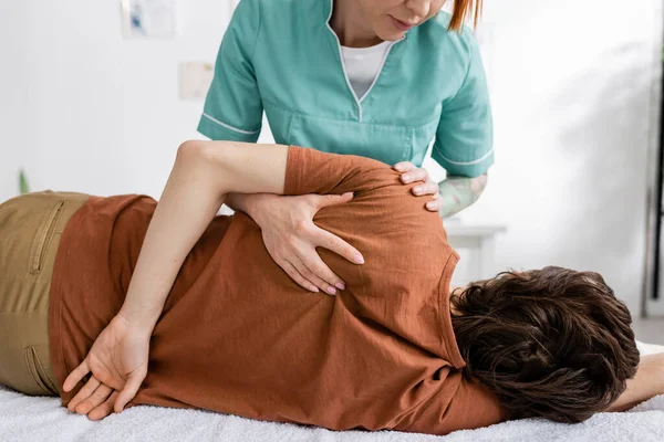 Fisioterapeuta massageando ombro doloroso do homem no centro de reabilitação — Fotografia de Stock