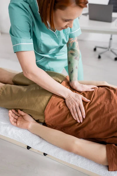 Manual therapist massaging painful back of man in recovery center — Stock Photo