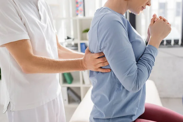 Cropped view of physiotherapist examining injured back of woman in consulting room — Stock Photo