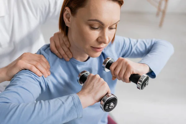 Woman training with dumbbells near physiotherapist in rehabilitation center — Stock Photo