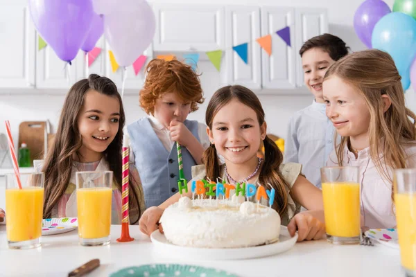 Group of happy preteen kids celebrating birthday next to tasty cake during party at home — Stock Photo
