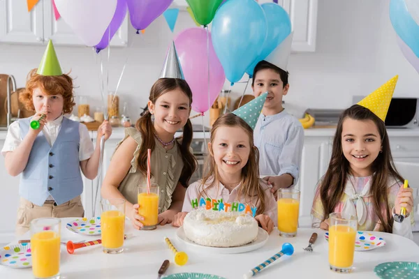 Group of happy kids celebrating birthday party next to cake with candles at home — Stock Photo