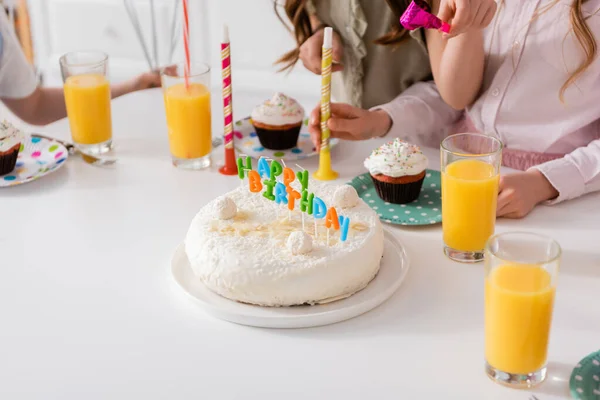 Hausgemachte Geburtstagstorte mit Kerzen neben Cupcakes und Gläsern Orangensaft — Stockfoto