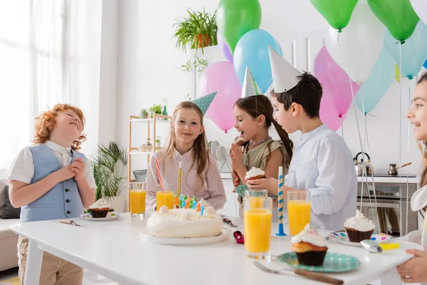Group of joyful children in party caps having fun during birthday party next to colorful balloons — Stock Photo