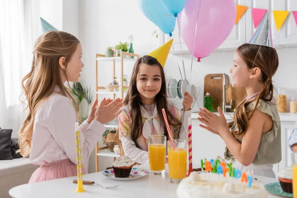 Cheerful preteen girls clapping hands and singing happy birthday song to friend — Stock Photo