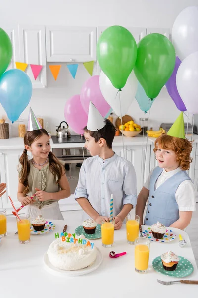 Glücklicher Junge und Mädchen, die sich bei Geburtstagsparty neben Kuchen anschauen — Stockfoto