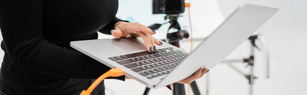 Partial view of african american content producer using laptop in blurred photo studio, banner — Stock Photo