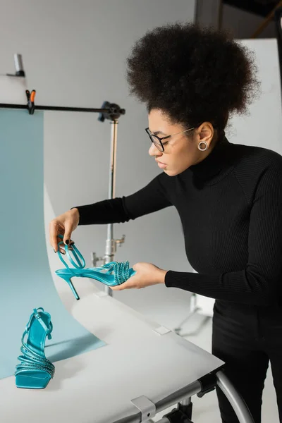 African American content manager con scarpe alla moda vicino al tavolo da tiro in studio fotografico — Foto stock