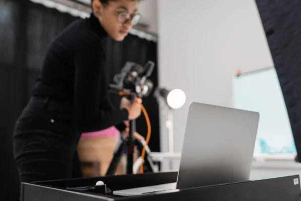 Laptop near blurred african american content manager with digital camera in photo studio — Stock Photo