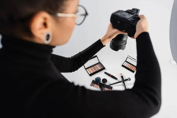 Blurred african american content maker taking photo of decorative cosmetics and beauty tools in photo studio — Stock Photo