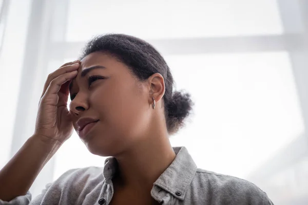 Depressed multiracial woman touching forehead at home — Stock Photo