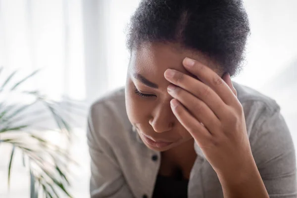 Jeune femme multiraciale souffrant de maux de tête à la maison — Photo de stock
