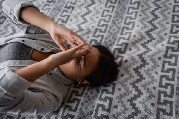 High angle view of multiracial woman with depression lying on bed at home — Stock Photo