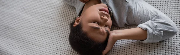 Vista dall'alto della donna multirazziale depressa sdraiata sul letto a casa, striscione — Foto stock
