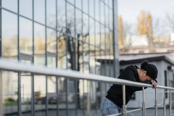 Depressed multiracial woman standing near railing outdoors — Stock Photo