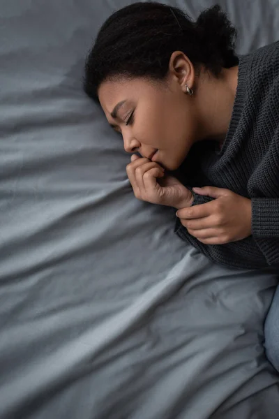 Top view of frustrated multiracial woman lying on bed at home — Stock Photo