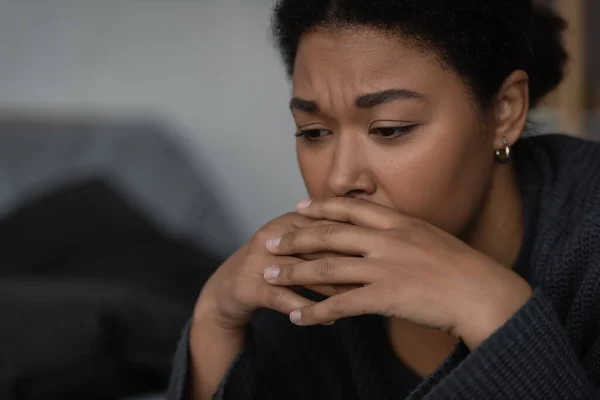 Displeased multiracial woman in sweater having apathy and looking away at home — Stock Photo