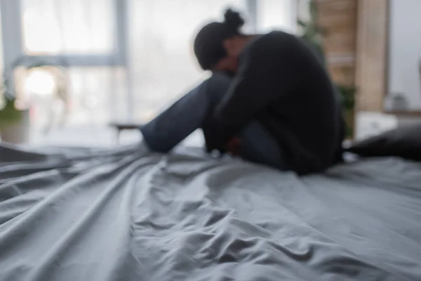 Mulher multirracial desfocada com depressão sentada na cama em casa — Fotografia de Stock