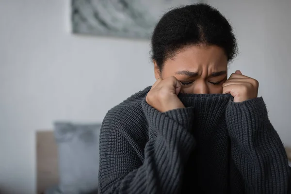 Мультирасовая женщина с психическими проблемами плачет в спальне дома — стоковое фото