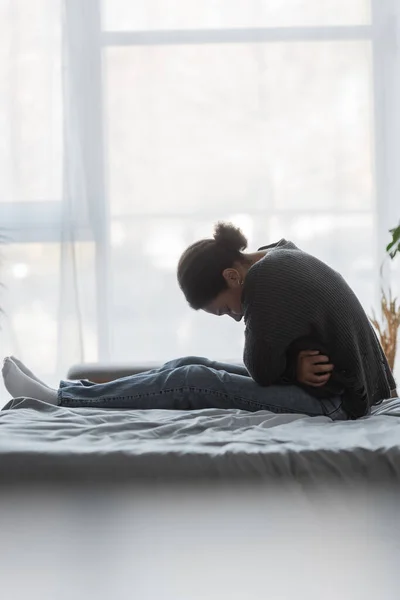 Junge multirassische Frau mit psychischen Problemen sitzt zu Hause auf dem Bett — Stockfoto