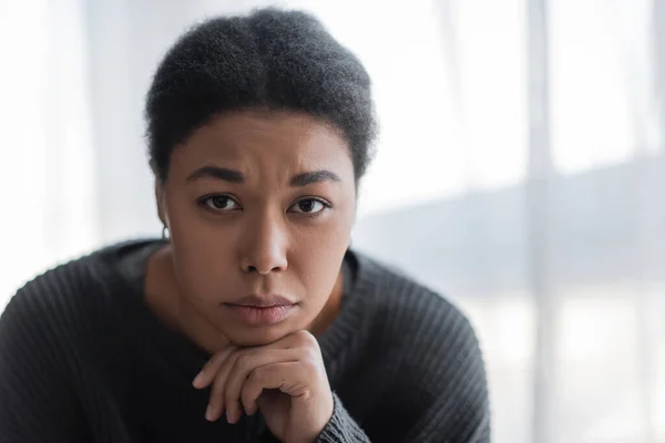Porträt einer jungen multirassischen Frau mit Depressionen, die zu Hause in die Kamera schaut — Stockfoto