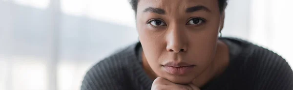 Jeune femme multiraciale avec dépression regardant la caméra à la maison, bannière — Photo de stock